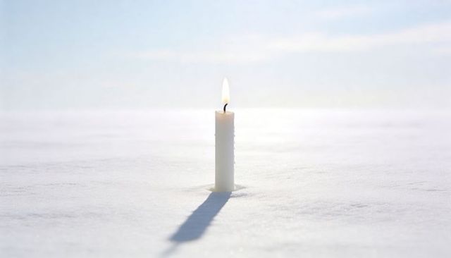 Burning candle on snowfield casting long shadow minimalist winter solitude hopeful glow