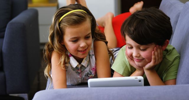 Happy Children Using Tablet Together While Lying On Couch - Download Free Stock Images Pikwizard.com