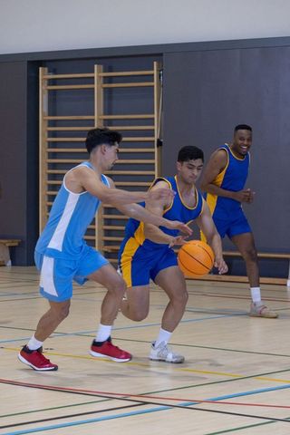 Diverse male athletes competing tenaciously on basketball court