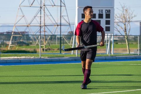 Field hockey player walking on turf holding stick