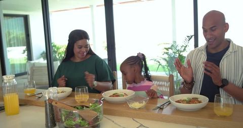 African american family enjoying pasta at kitchen island in sunlit modern open-plan home