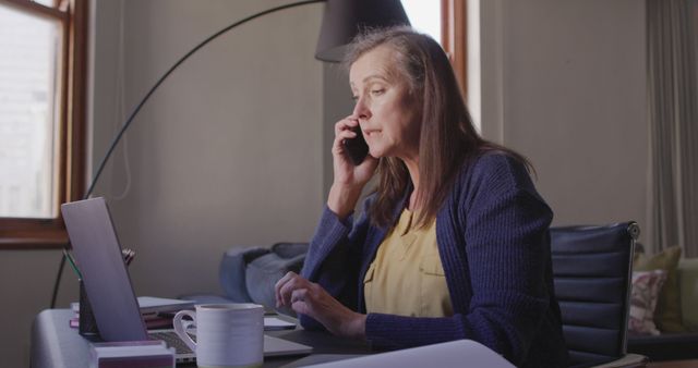 Mature Woman Working From Home Taking Phone Call and Using Laptop - Download Free Stock Images Pikwizard.com