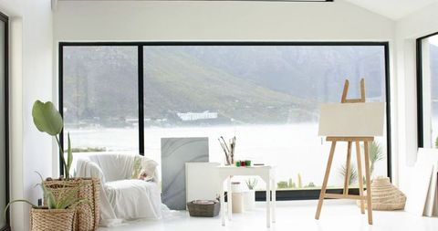 Blank canvas on wooden easel facing lake in bright scandinavian art studio bathing in light