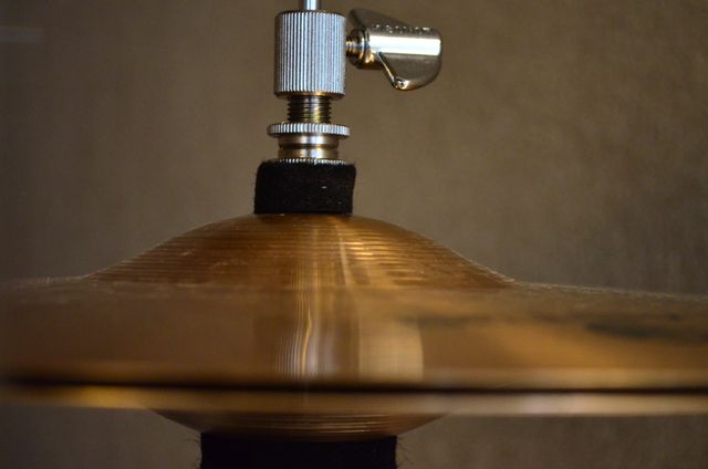 This close-up shot of a cymbal with mounting hardware can be used for music-related articles, tutorials, or blogs focused on drumming or musical instruments. It can also be used for promotional materials for music studios or music equipment stores.