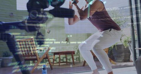 Performing squat holding dumbbell while filming with tripod camera, code overlay