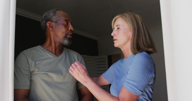 Senior couple appears tense while talking at home, indicating a moment of conflict or argument. This image is useful for articles related to relationships, marriage problems, senior lifestyle discussions, or emotional well-being in older adults.