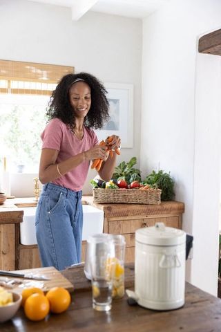 African american woman peeling carrots in rustic farmhouse kitchen preparing healthy meal