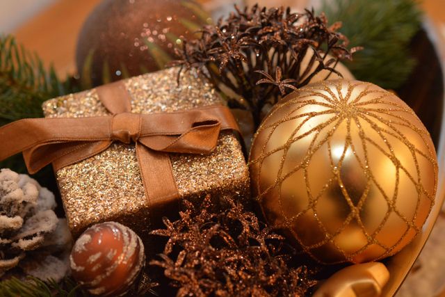 Golden Christmas ornaments and sparkling gift create festive atmosphere. Great for holiday cards, Christmas event promotions, seasonal marketing, home decor inspiration, and festive celebration features.