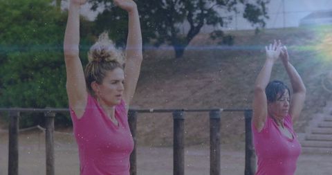 Women Stretching in Matching Pink Outfits at Outdoor Gym