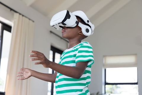 African american boy wearing vr headset exploring virtual world at home