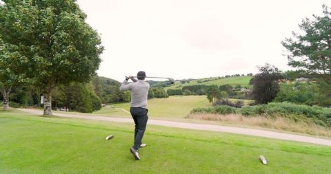 Golfer performing powerful swing on tee with scenic view