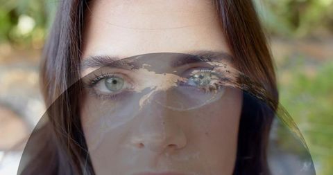 Introspective woman portrait with translucent globe overlay double exposure green eyes