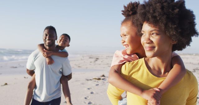 Afro-American parents giving piggyback rides to their children while enjoying a playful and joyful day at the beach. Ideal for use in images depicting family bonding, summer vacations, outdoor fun, and happy moments. Perfect for promoting family-oriented activities, travel destinations, and lifestyle content.