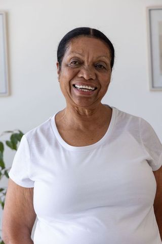 Senior african american woman smiling in white t-shirt, bright minimalist home portrait
