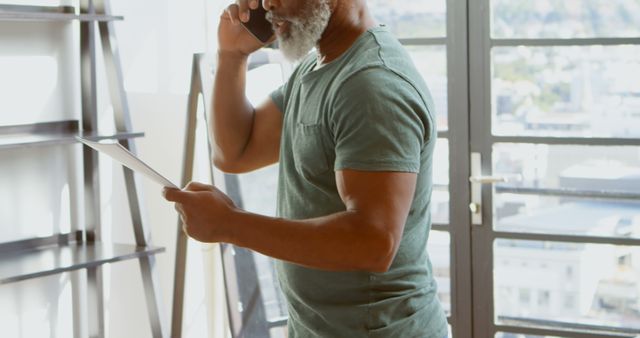 Mature Man Using Phone and Tablet in Modern Office Setting - Download Free Stock Images Pikwizard.com