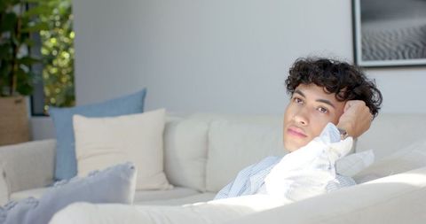 Man Relaxed on Sofa in Sunlit Modern Living Room with Decor
