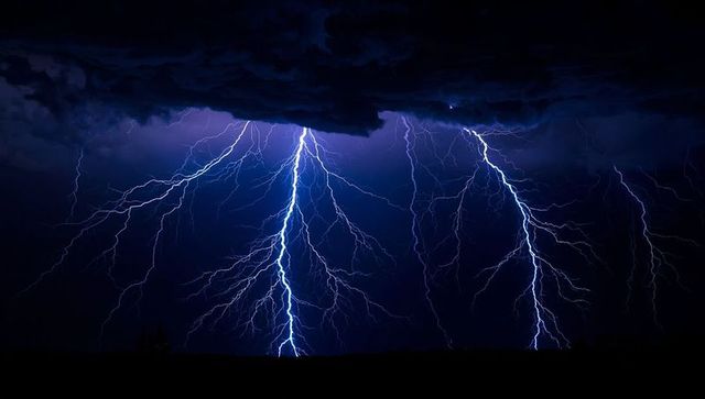 Dramatic nighttime lightning striking open plain