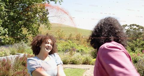 Smiling friends enjoying sunny garden walk, candid outdoor lifestyle moment