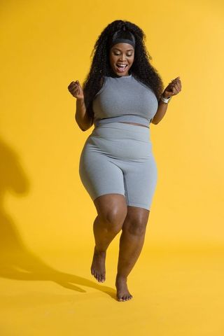 African american woman jumping in gray activewear on vibrant yellow background