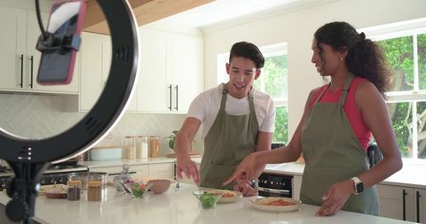 African American creators filming cooking tutorial on bright kitchen island with ring light