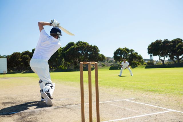 Cricket player in action, batting on a sunny day on a well-maintained field. Ideal for use in sports articles, promotional materials for cricket events, or advertisements for sports equipment.