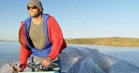 Man steering boat on tranquil waters during solo adventure