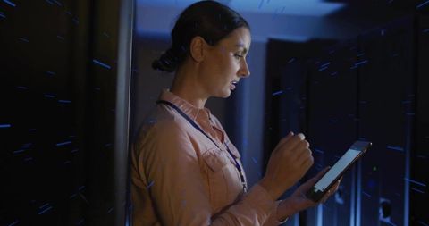 Female IT Technician Inspecting Server Rack with Tablet in Blue-Lit Data Center at Night