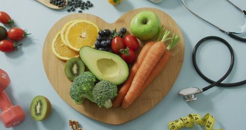 Assorted fresh produce on heart shaped board with stethoscope for healthy eating
