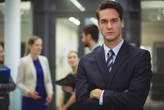 Businessman standing with arms crossed in the office - Download Free Stock Photos Pikwizard.com