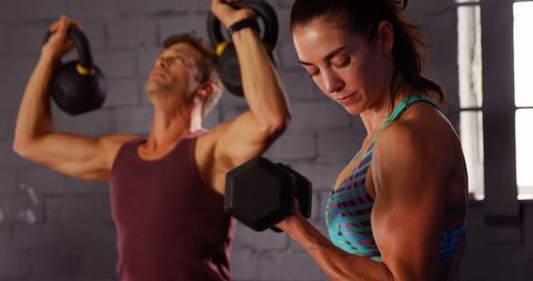 Man and Woman Focusing on Strength Training in Gym
