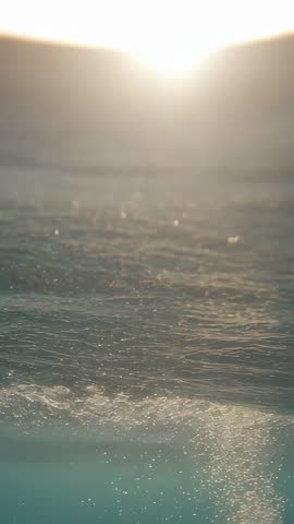Vertical Sunrise Over Ocean Horizon with Sparkling Droplets and Calm Dawn Motion