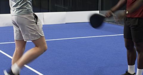 Diverse players enjoying paddle tennis game on court