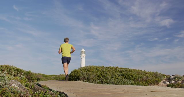 Senior Man Jogging on Boardwalk Near Lighthouse Against Sunny Sky - Download Free Stock Images Pikwizard.com