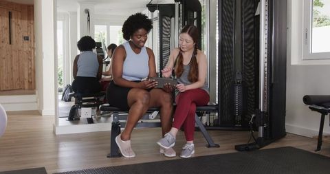 Fitness Trainer with Client Using Tablet in Gym Environment