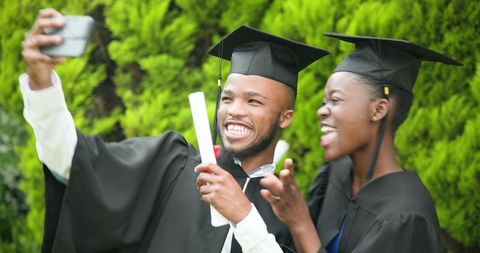 Joyful Graduates Capturing Memories with Selfie Outdoors