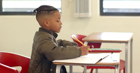 Focused young boy writing at school desk with determination