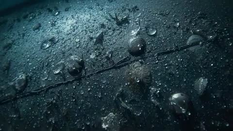 Camera sliding over wet ship hull panel showing droplets merging and running along rivet seam