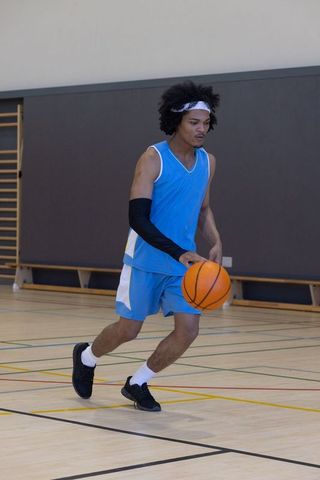 Athlete Dribbling Basketball on Indoor Court in Blue Jersey