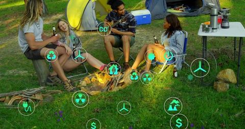 Friends camping around campfire at dusk with guitar and eco technology icons overlay