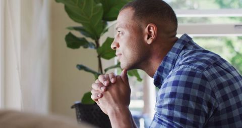 Contemplative Man Looking Out Window in Peaceful Home Setting