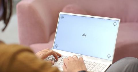 African American man typing on white laptop on pink sofa in modern home workspace