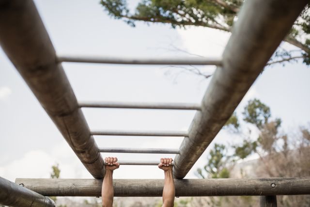 Fit man climbing monkey bars during obstacle course in boot camp
