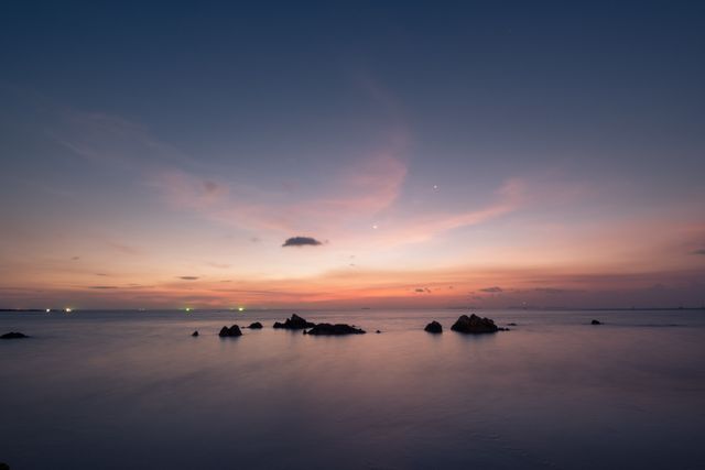Serene Twilight Over Calm Ocean with Rocks and Twilight Sky - Download Free Stock Photos Pikwizard.com