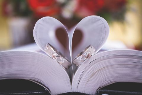 Rings resting in heart-shaped book pages with floral background
