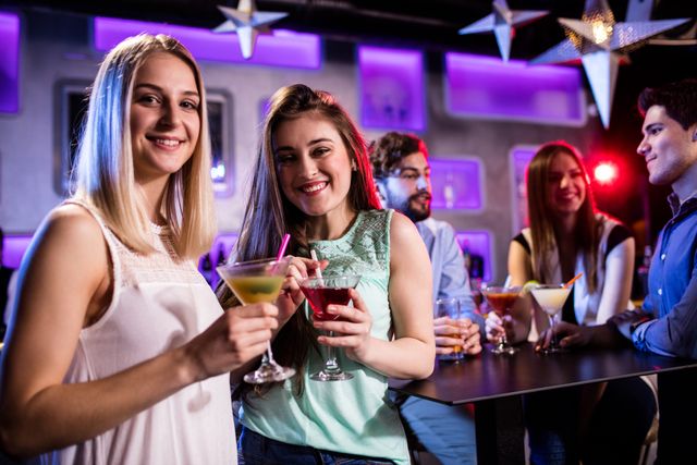 Group of friends enjoying cocktails at a trendy bar. Perfect for illustrating nightlife, social gatherings, and celebrations. Ideal for use in advertisements, social media posts, and articles about nightlife, friendship, and leisure activities.