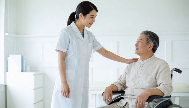 Nurse comforting senior man in wheelchair, smiling caregiver showing gentle compassion