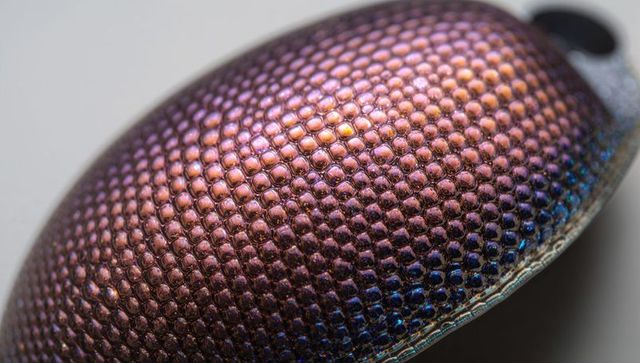 Iridescent honeycomb dome pendant reflecting purple gold blue macro texture