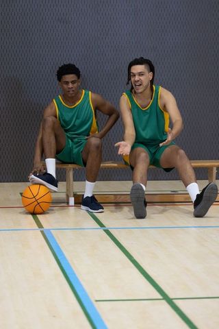Athletes in green jerseys resting on bench during intense game