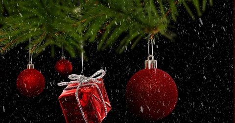 Festive Christmas Ornaments and Gift on Pine Branch with Snowfall