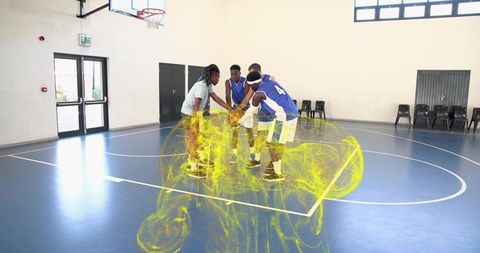 Competitive basketball team huddling with yellow energy swirl on indoor court